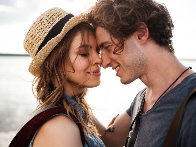 Влюбленная пара стоит на фоне моря 