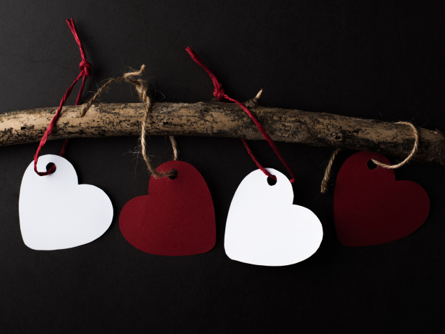 Бумажные сердечки на ветке на черном фоне