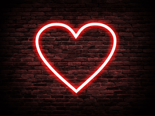Красное неоновое сердце на кирпичной стене 