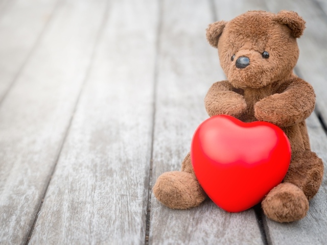 Медвежонок Тедди с красным сердцем сидит на столе
