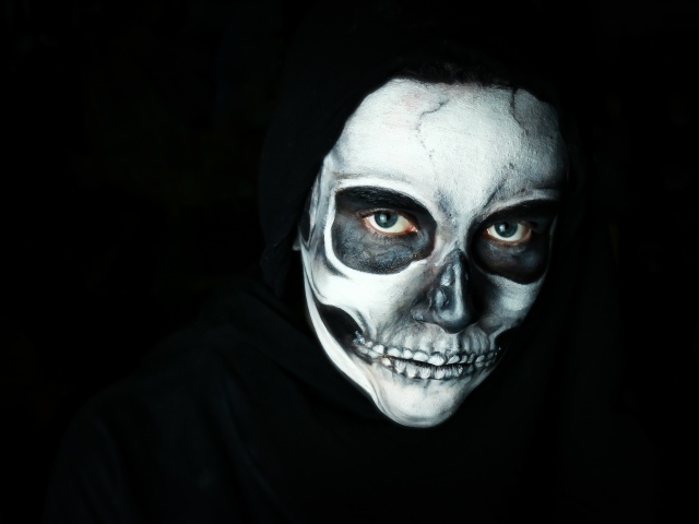 Мужчина в черном наряде с гримом на лице на Хэллоуин