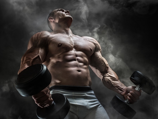 Мужчина бодибилдер с тяжелыми гантелями в руках