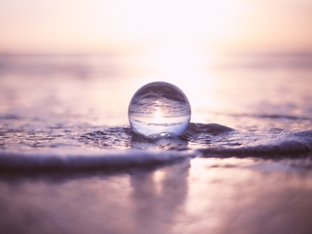 Прозрачный стеклянный шар лежит на пене в море