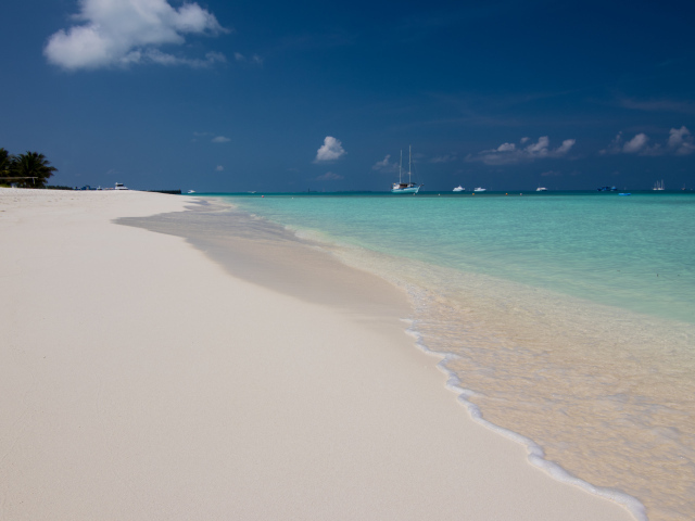 Спокойные волны на белом горячем песке под голубым небом