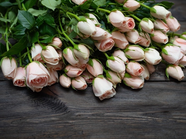 Большой букет розовых роз на деревянном столе 