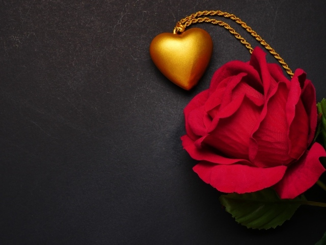 Искусственная красная роза с кулоном на сером фоне