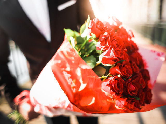 Большой красивый букет красных роз в руках мужчины 