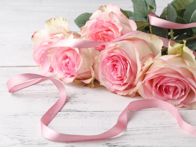Букет розовых роз с лентой на белом столе 