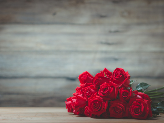 Букет красных роз на фоне деревянной стены 