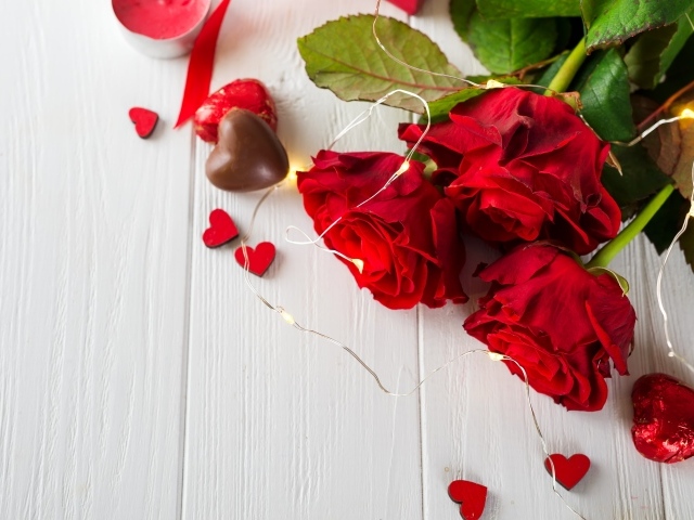 Букет красных роз с конфетами на столе