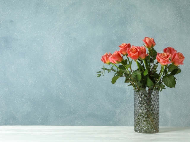 Букет роз в стеклянной вазе на сером фоне