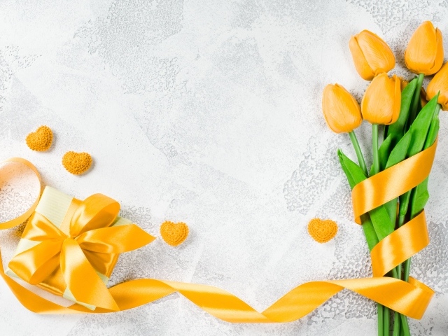 Букет желтых тюльпанов с лентой и подарком на сером фоне