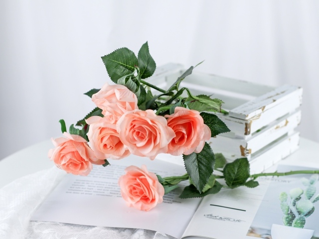 Розовые цветы лежат на столе на журнале