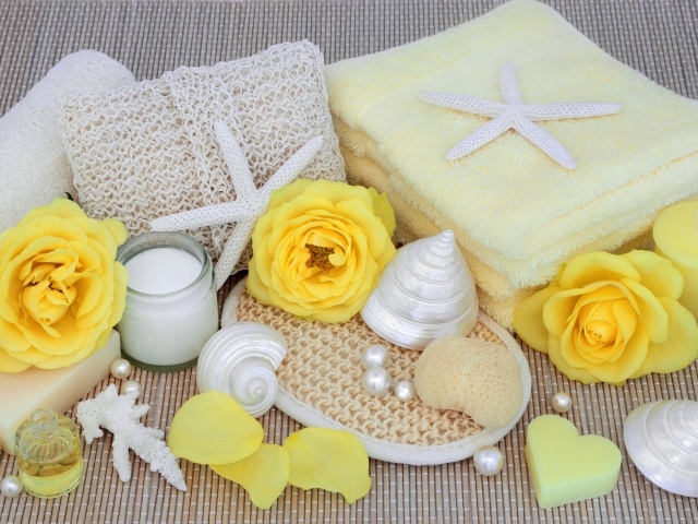 Желтые розы на столе с полотенцем, ракушками и мылом