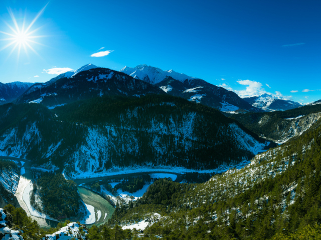 Яркое солнце в голубом небе над заснеженными горами, Швейцария 