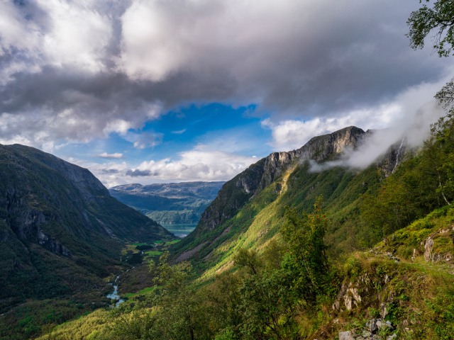 Покрытые зеленой растительностью горы под белыми облаками, Норвегия