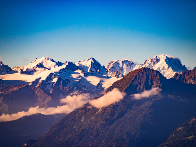Заснеженные вершины гор под голубым небом