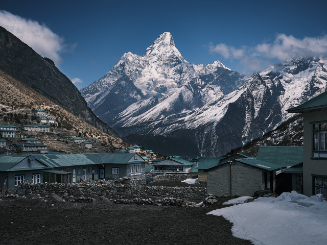 Поселок на фоне заснеженных гор под голубым небом 