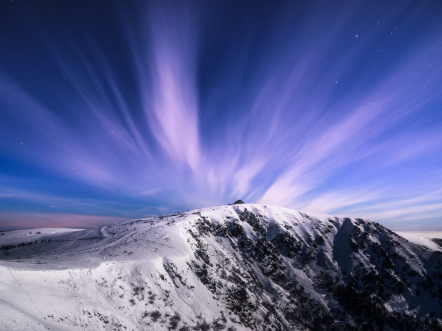 Белые облака в голубом небе над заснеженными горами