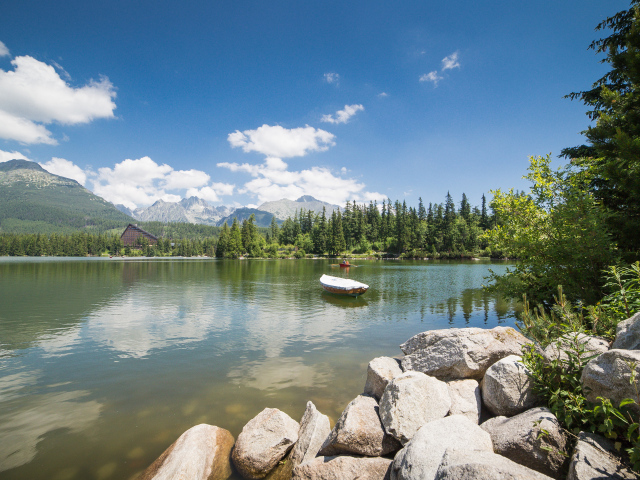 Лодка в озере на фоне гор под голубым небом