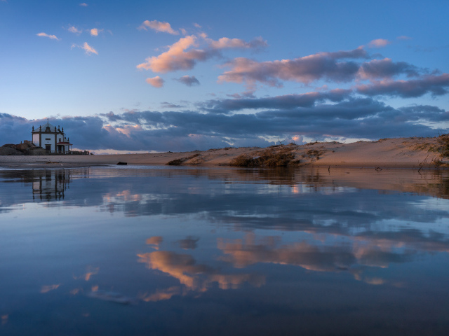 Облака отражаются в спокойной воде озера 