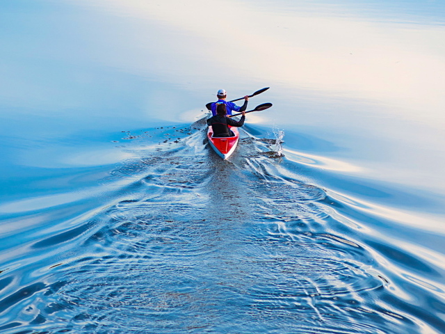 Два спортсмена на лодке плывут по реке 