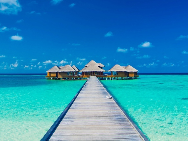 Деревянный мост к домам на сваях в голубом океане 