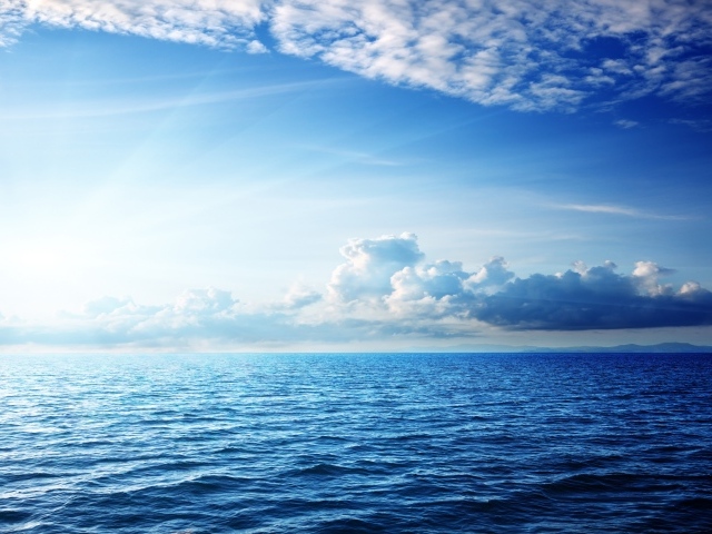 Спокойное синее море под ясным небом с белыми облаками