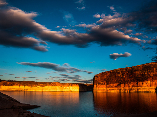 Скалы  в воде под голубым небом с облаками 
