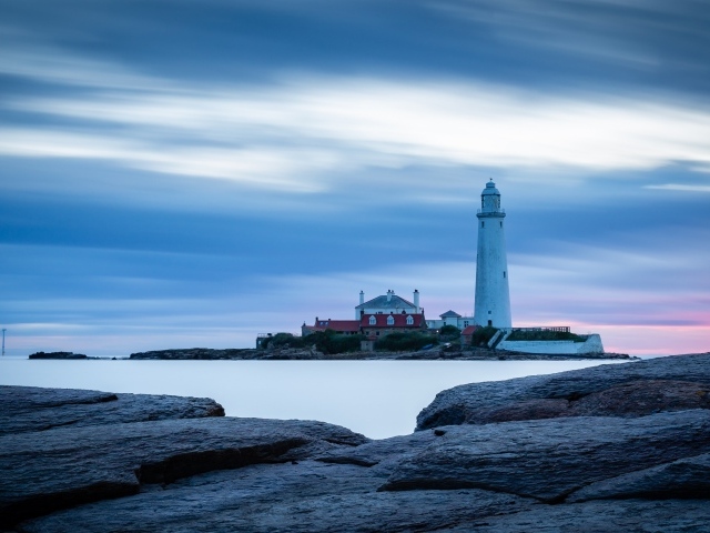 Вид с каменного берега на маяк в море 