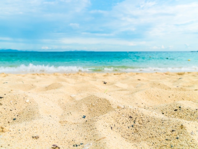 Горячий желтый песок на пляже у океана летом 