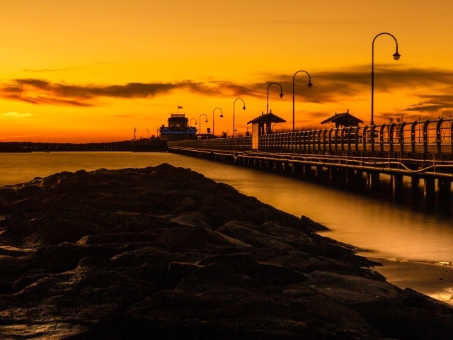 Длинный мост на морском побережье на закате 