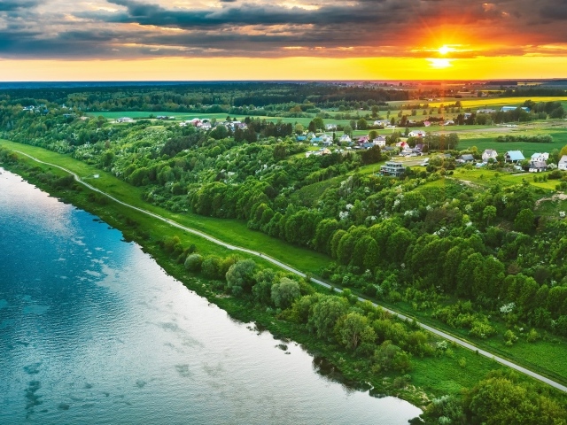 Закат солнца над городом у реки, вид с высоты 