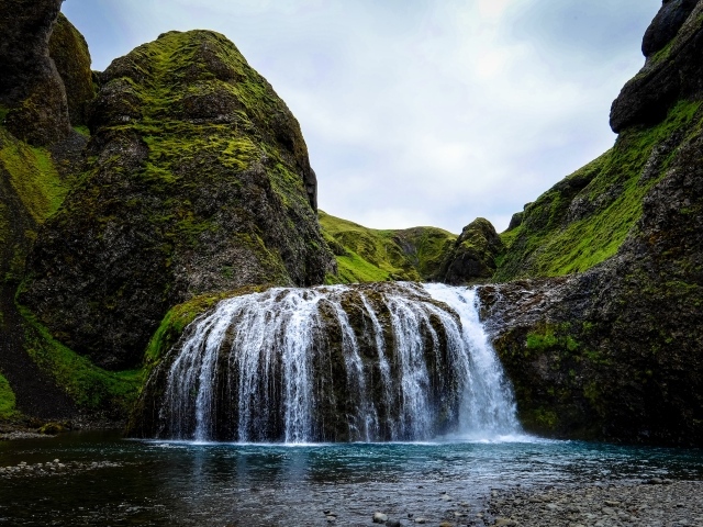 Белая вода водопада стекает по покрытым мхом скалам