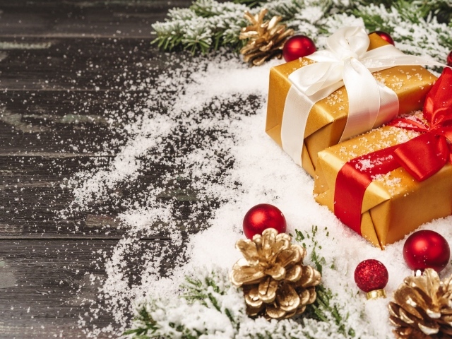 Два новогодних подарка на столе с еловыми ветками 