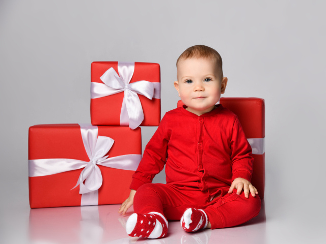 Милый малыш в красном костюме с подарками на новый год 