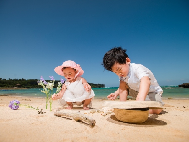 Маленькие дети азиаты играют на песке у моря 