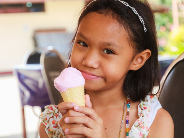 Маленькая девочка азиатка с мороженым в руке