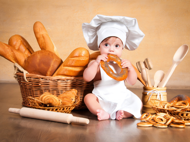 Маленький мальчик с хлебобулочными изделиями на столе 
