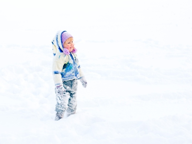 Маленькая веселая девочка гуляет по снегу