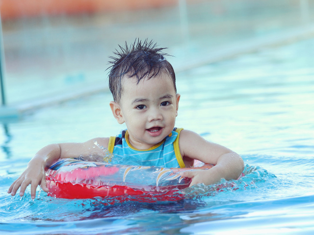 Маленький ребенок со спасательным кругом в бассейне 