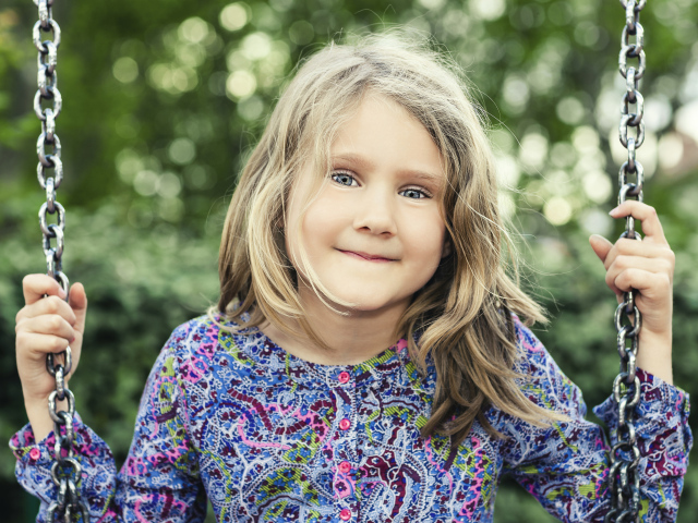 Маленькая милая голубоглазая девочка на качели