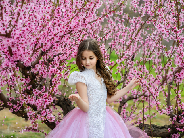 Маленькая девочка в красивом платье у дерева с розовыми цветами
