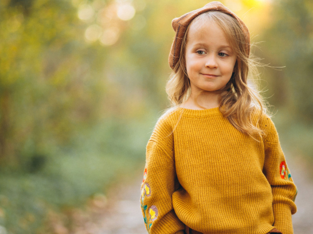 Маленькая девочка в свитере гуляет в лесу