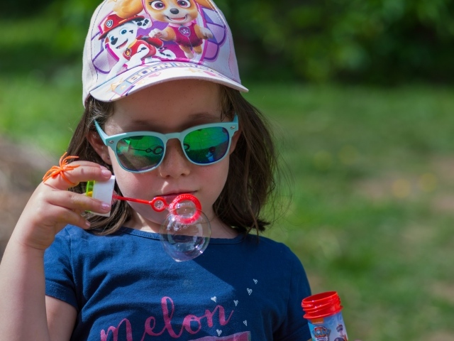 Маленькая девочка в очках с мыльными пузырями