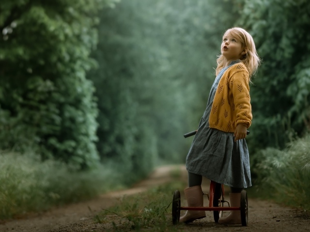 Маленькая девочка на трехколесном велосипеде 