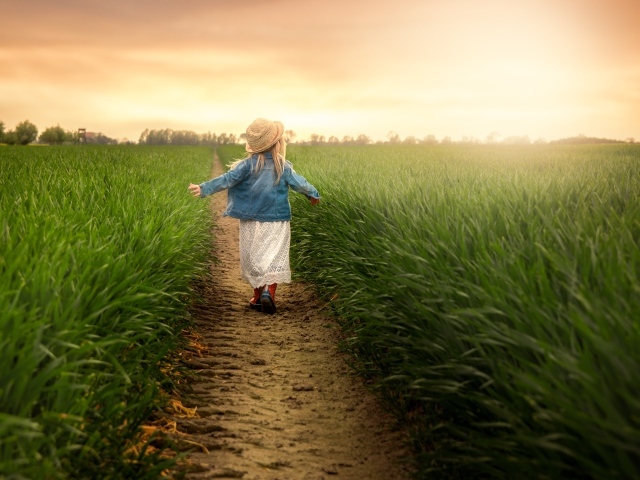Маленькая девочка идет по полю с зеленой травой 