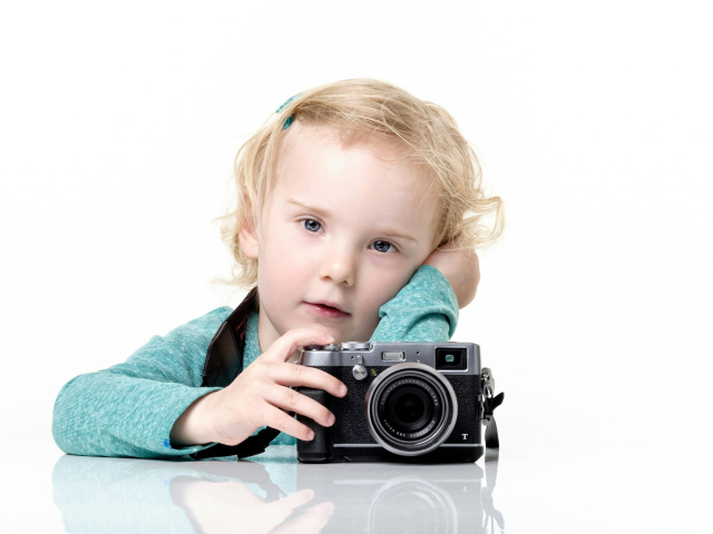 Маленькая девочка с фотоаппаратом на белом фоне