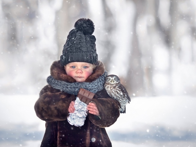 Маленькая девочка с шоколадкой в руках на улице зимой