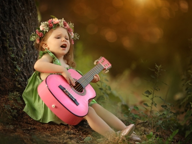 Маленькая девочка с гитарой под деревом 